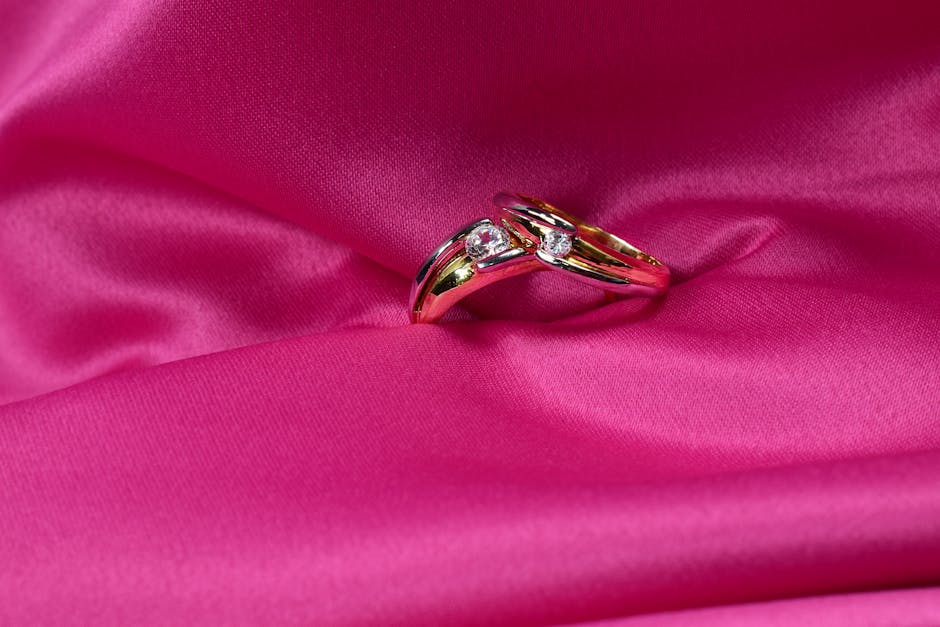 Close-up of a luxurious gold ring with diamonds elegantly displayed on pink silk fabric.