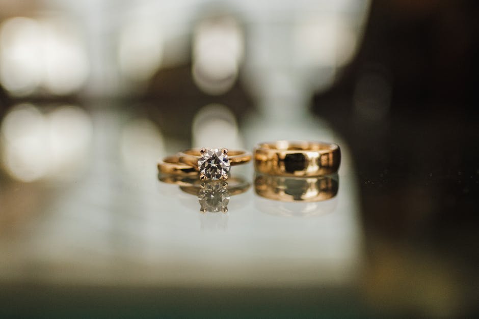 Beautiful diamond and gold wedding rings on a glass surface, showcasing elegance and luxury.