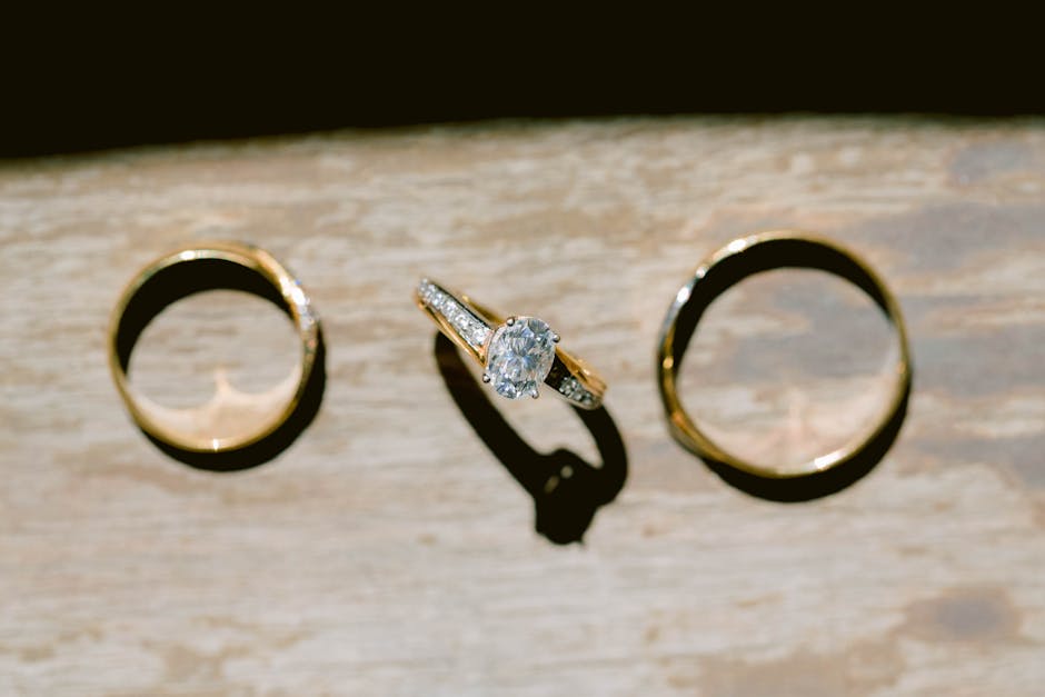Close-up photo of gold and diamond rings on a wooden surface under natural light.